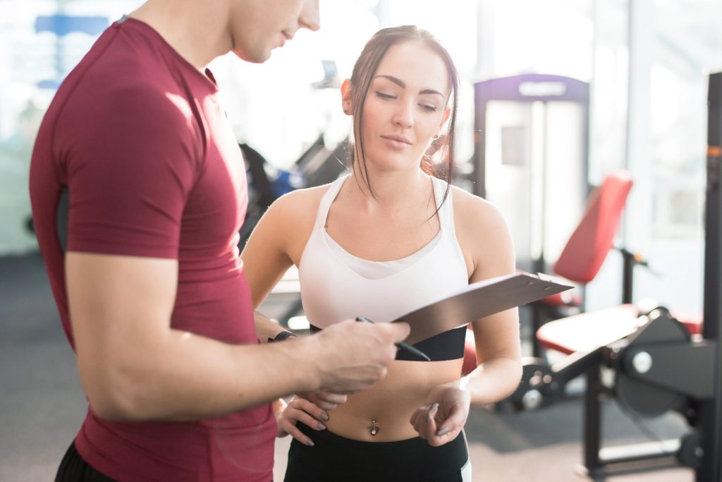 Girl at the gym looking at the results with her coach