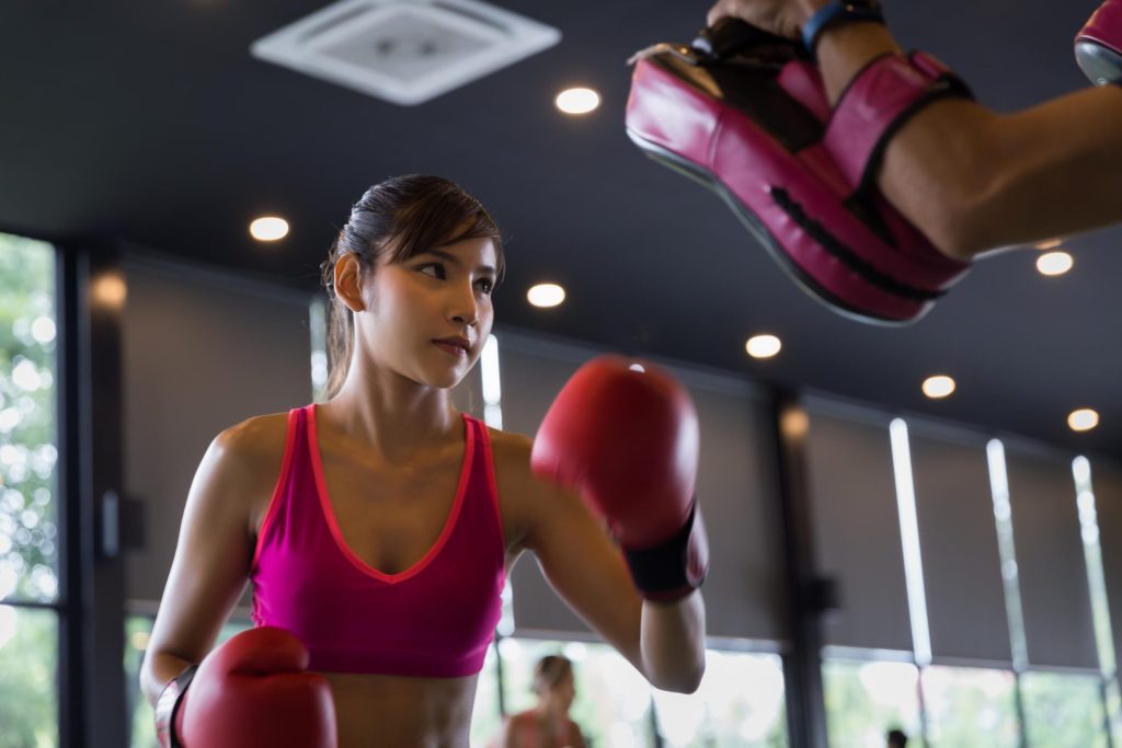 Girl playing boxing with her coach at the gym