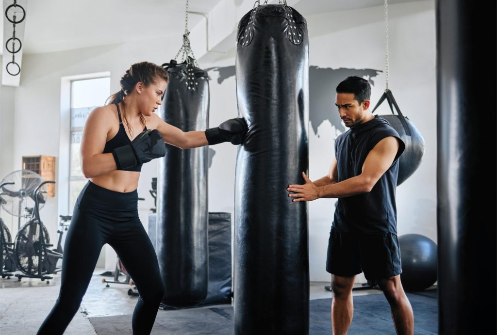 Girl playing boxing at the gym with the help of her coach