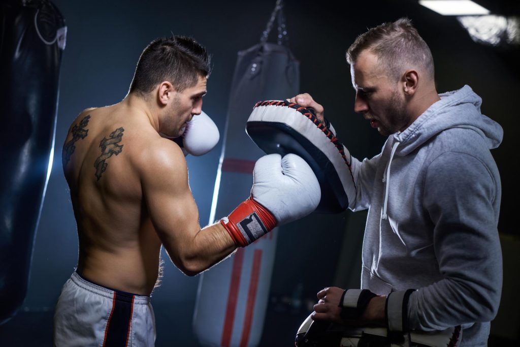 man playing boxing at the gym with his coach